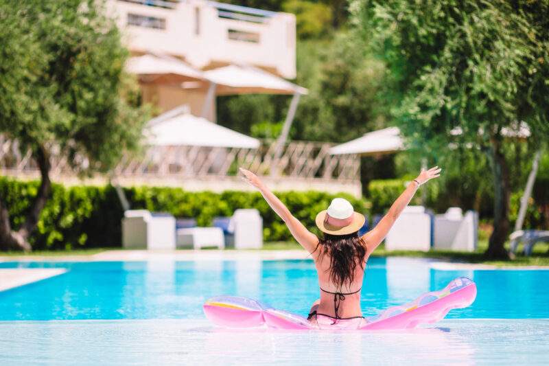 woman with hands up sitting on pool floatie