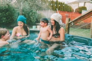 women and young boys smiling in a hot tub