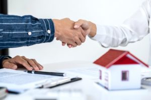 people shaking hands over miniature house