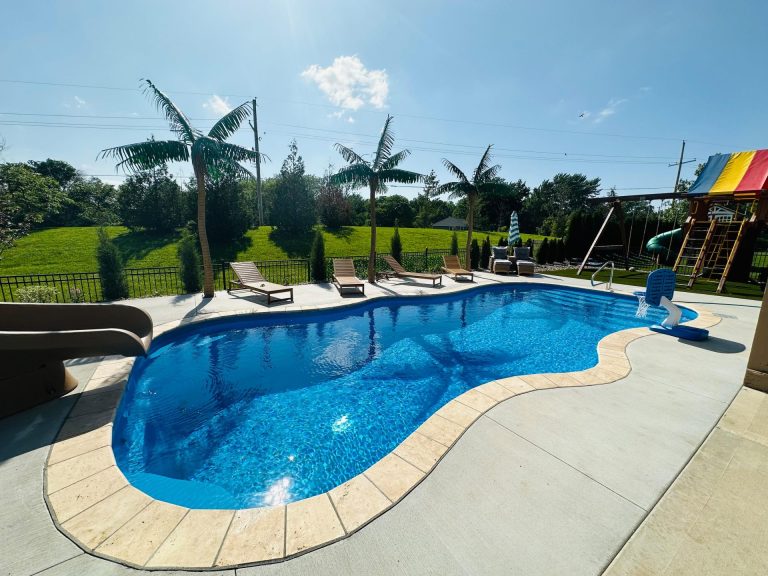 Freeform fiberglass pool with slide and seating area - Pools By York