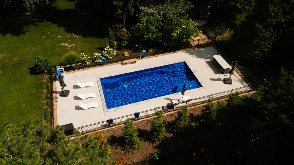 Aerial view of a rectangular fiberglass pool in a wooded backyard