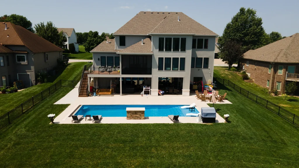 Rectangular fiberglass pool and patio behind a two-story home