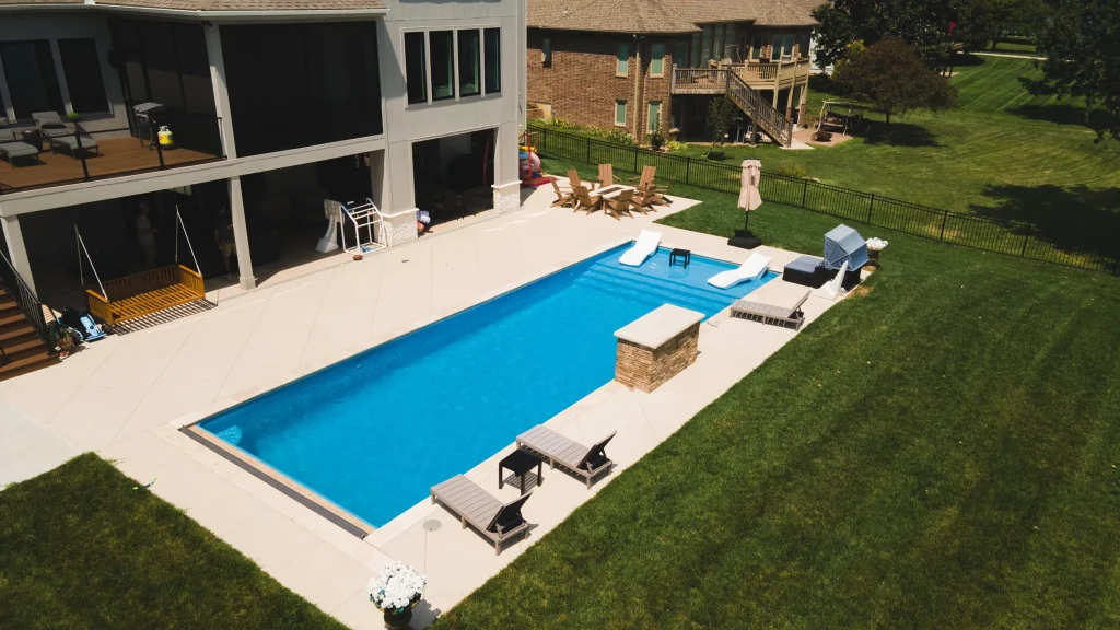 Rectangular fiberglass pool with lounge chairs behind a modern home