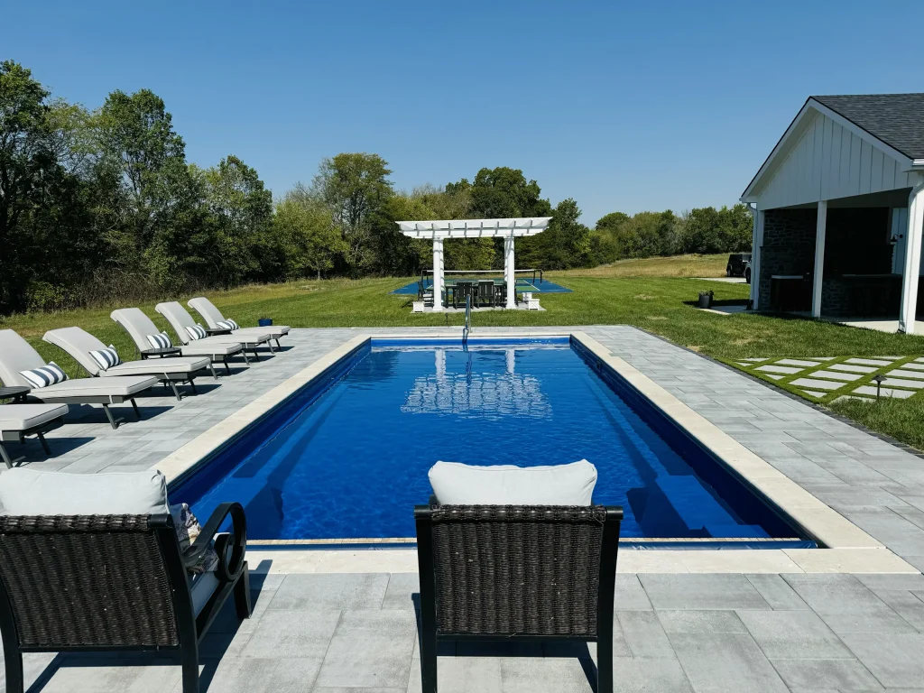 Rectangular fiberglass pool with lounge chairs and a white pergola