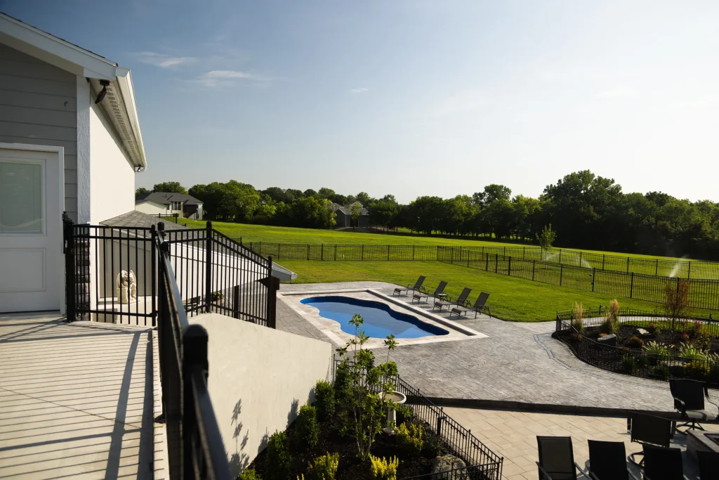 Elevated view of a backyard fiberglass pool and patio from a deck