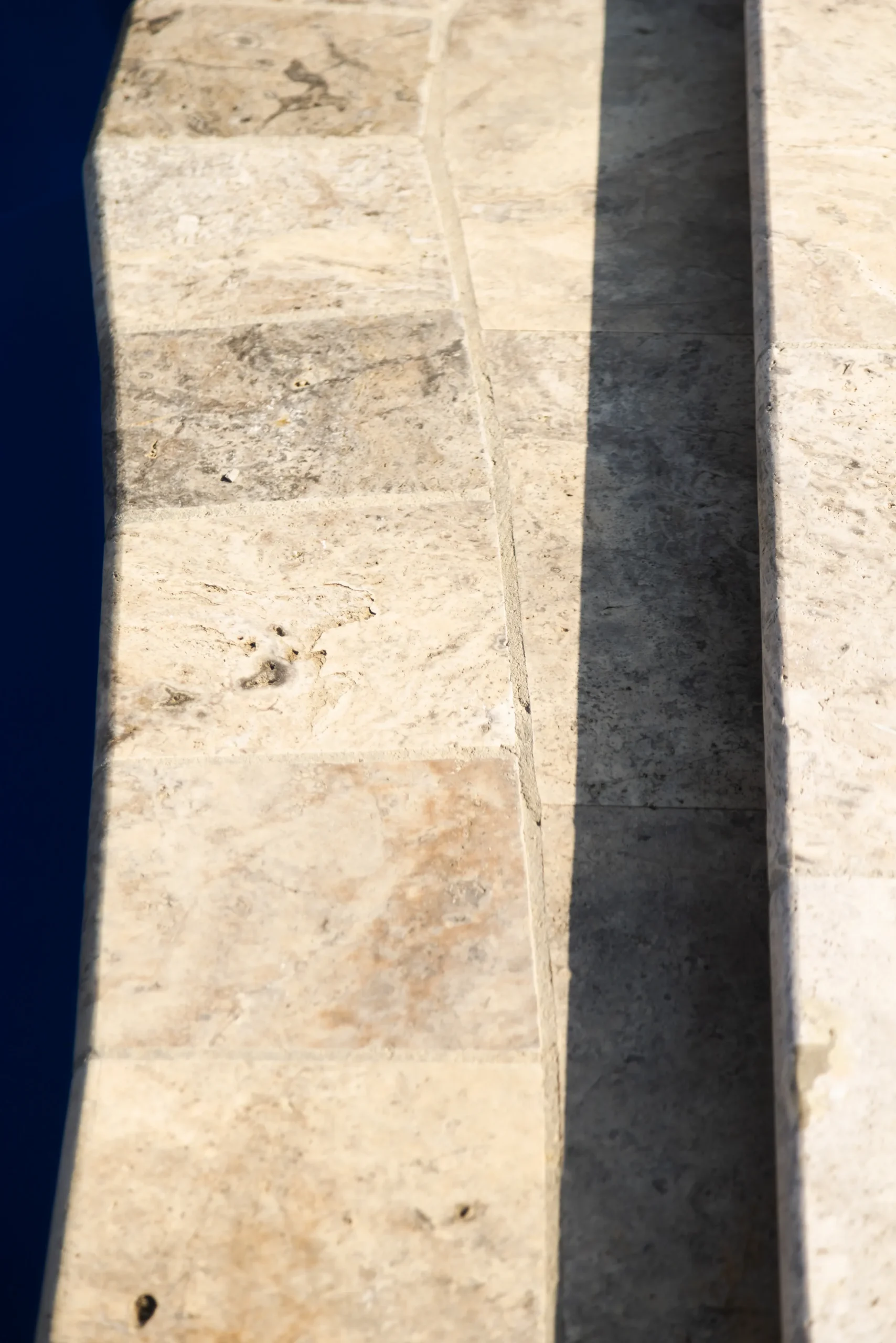Close-up of travertine coping along a fiberglass pool edge