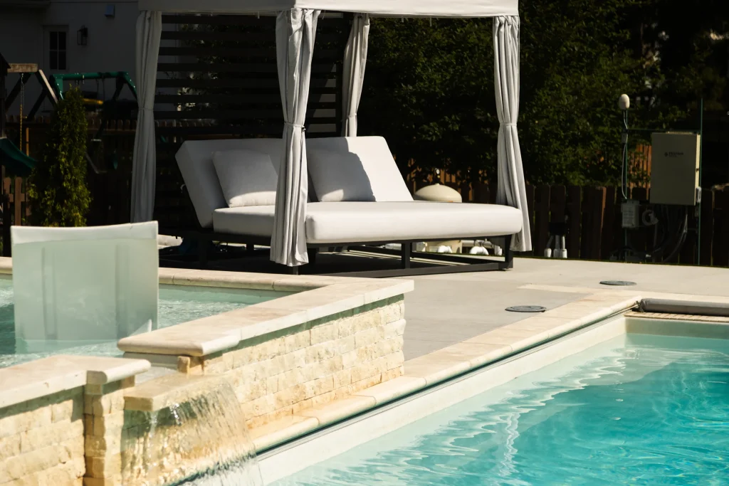 Fiberglass pool with stacked stone water feature and poolside cabana