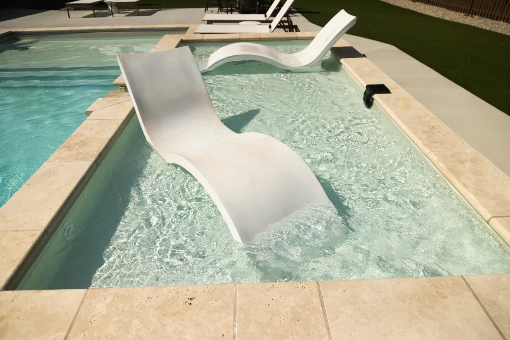 White in-water lounge chairs on a fiberglass pool tanning ledge