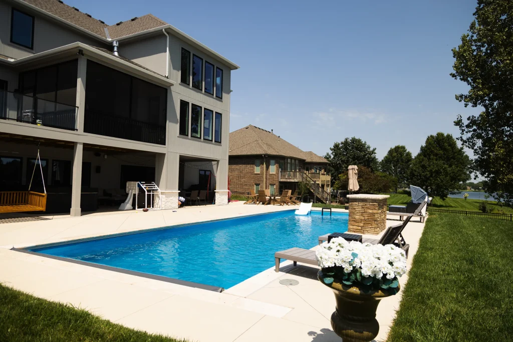 Rectangular fiberglass pool behind a multi-story lakefront home