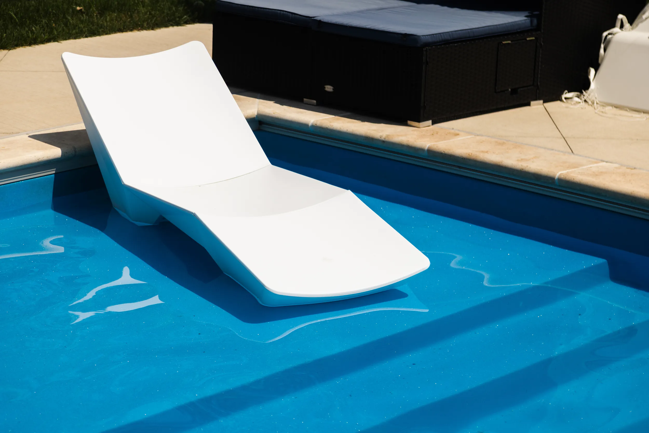 White lounger on a fiberglass pool tanning ledge with entry steps